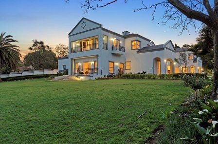 Mansion exterior with large lawn at dusk